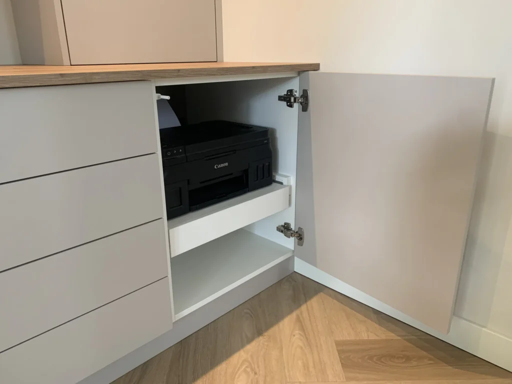 Printer op een uittrekbare plank achter een kastdeur in de thuiswerkplek in Boskoop